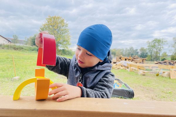 Dítě si hraje venku s duhovou pyramidou