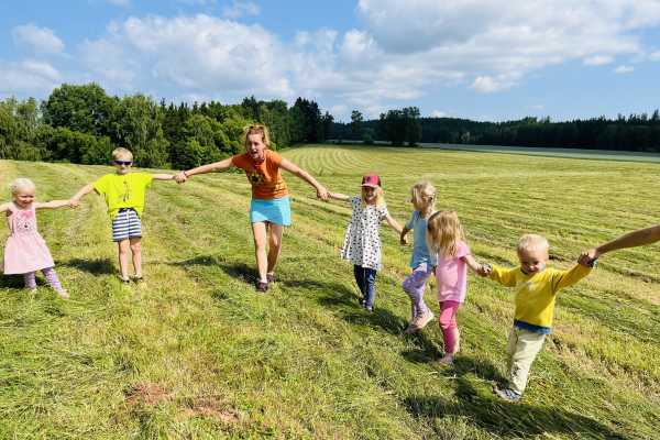 Děti v lesní školce si hrají na louce.