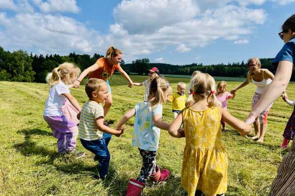 Děti v lesní školce se v kruhu drží za ruce.